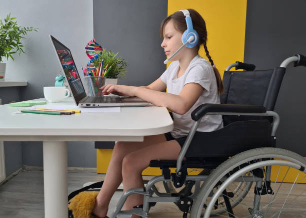 istock Young Girl Sitting in Wheelchair Using Laptop 2148692908