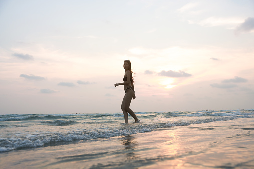 Beautiful woman playing in the sea In the sunset, a Happy female enjoys and fun outdoor activity lifestyle on a holiday travel vacation at the sea