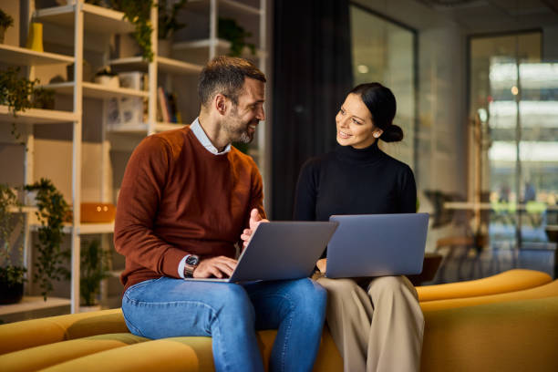 istock Two business colleagues looking at each other while working over laptops. 2148693148