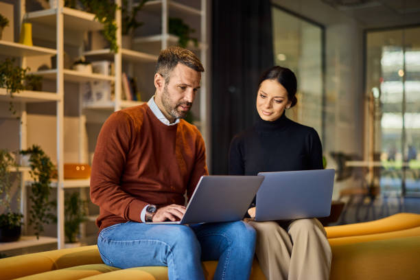 istock Business people working together over laptops, sitting next to each other, working on the same project. 2148693163