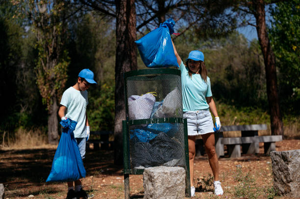 istock Woman and boy volunteers throwing garbage into the dumpster. 2148693501
