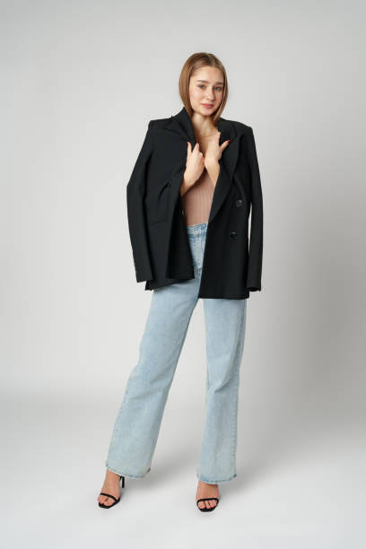 istock Young Woman Wearing Black Jacket and Jeans posing on gray background studio shot . 2148695134