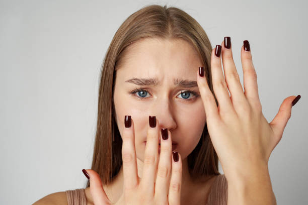 istock Scared woman covering her face with hands over gray background 2148695991