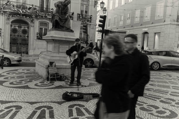 Lisbon, POrtugal - December 23, 2023: A street musician plays a guitar at the Largo de Camões square in Lisbon downtown.
