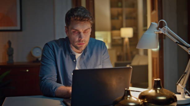 istock Focused guy browsing internet on pc at dark home closeup. Man typing laptop 2148697911