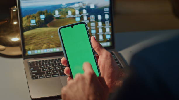 istock Unrecognizable guy scrolling telephone green screen on laptop workplace closeup 2148698015