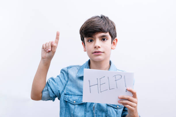 istock Young little boy kid holding paper sing with help message asking for protection surprised with an idea or question pointing finger with happy face, number one 2148698110