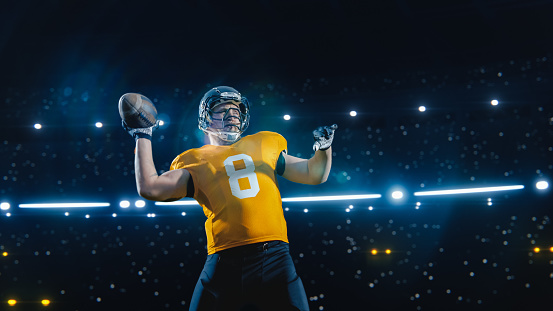 Aesthetic Shot of Athletic American Football Player Throwing a Ball on Black Background Under Spotlight. Professional Caucasian Athlete Plays Successful Pass With Teammates During Championship Match