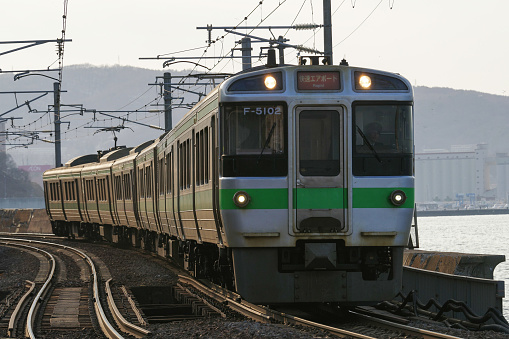 Otaru-city, Hokkaido, Japan - April 13, 2024 : 721 Series Rapid train “Airport” running on the curve
