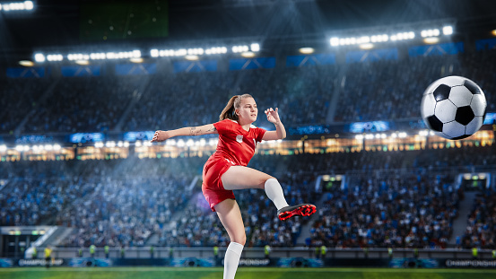 Aesthetic Shot Of Professional Female Soccer Football Player Jumping And Kicking A Ball on Stadium WIth Crowd Cheering. Goal on International Championship Match on Arena Full Of Excited Fans.