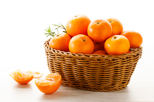 Fresh mandarin oranges fruit or tangerines in wooden basket. Closeup.