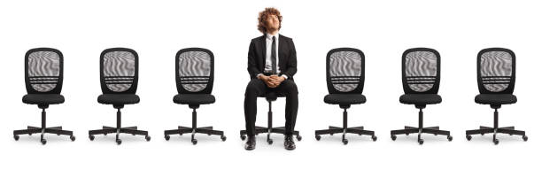 istock Empty office chairs and a young professional man sitting in the middle and looking up 2148699308