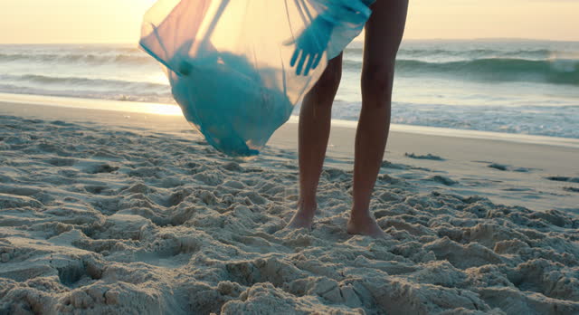 Hand, plastic bag and garbage for cleaning beach, sunset or outdoor for sustainability, recycling or marine ecology. Volunteer person, trash and bottle on sand for healthy environment, sea or future