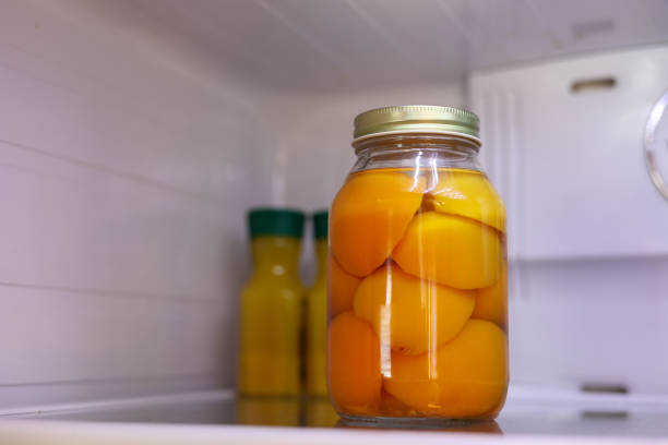 A jar of fresh sliced peaches inside a a refrigerator