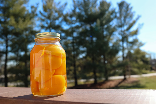 A jar of sliced peaches on a wooden table