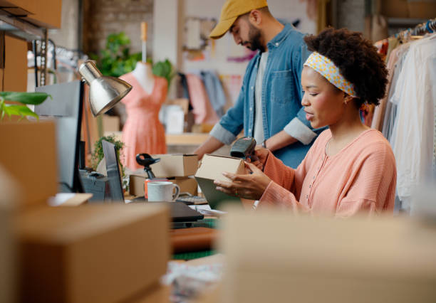 istock Business people, scan and service with a package, retail and store with parcel, cooperation or fashion designer. Label, staff or cashier with cardboard or stock barcode with clothing shop or teamwork 2148700645