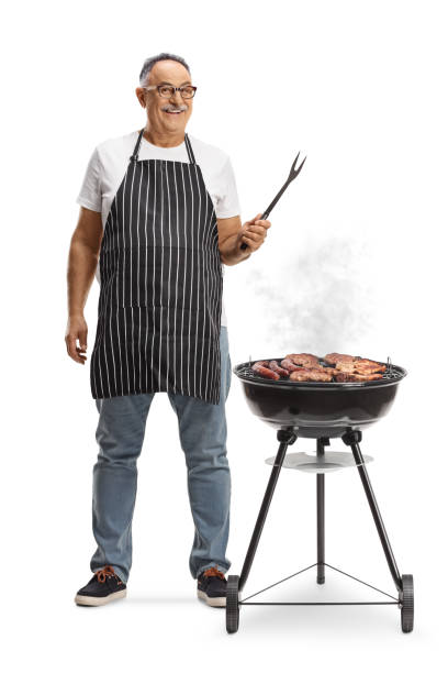 istock Mature man next to a portable barbecue grill holding a fork 2148701275
