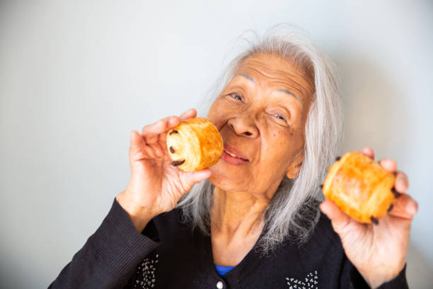 istock Elderly Woman Holding Two Chocolate Croissants 2148701373