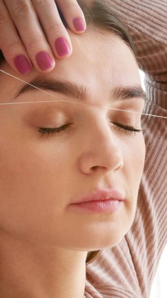 istock Cosmetologist plucks client eyebrows by thread in the beauty salon 2148701812