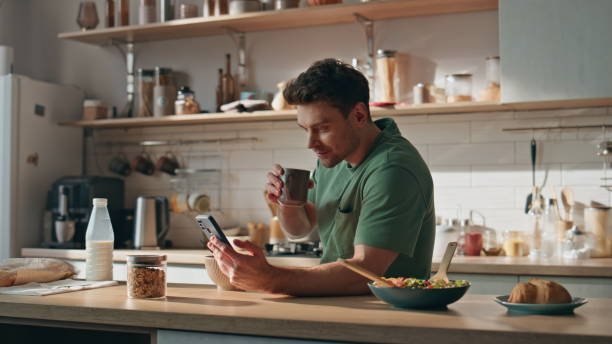 istock Drinking businessman surfing cellphone kitchen closeup. Guy enjoying breakfast 2148703921