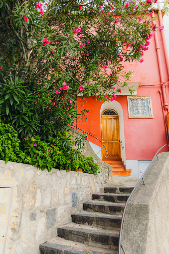Walking the steps in the authentic Italian streets with pink houses during summertime  in Positano city, South Italy