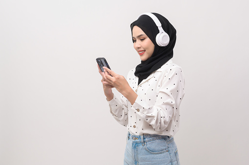 Young beautiful muslim woman wearing headset on white background