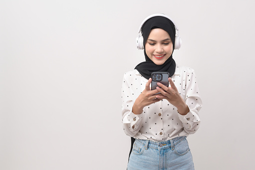 Young beautiful muslim woman wearing headset on white background