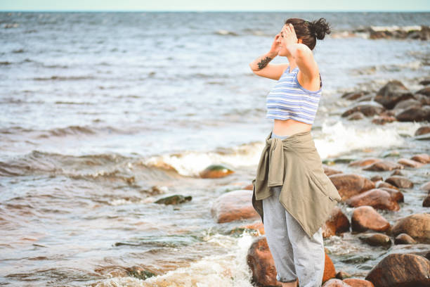 Beautiful, idyllic seaside landscape concept. Rocks stones, water sea horizon on cloudy day, woman watching beautiful landscapes.