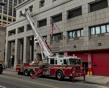 firefighters on a ladder against a building (unrecognizable, no face) FDNY new york fire fighters department on fire engine (emergency response agency) fireman