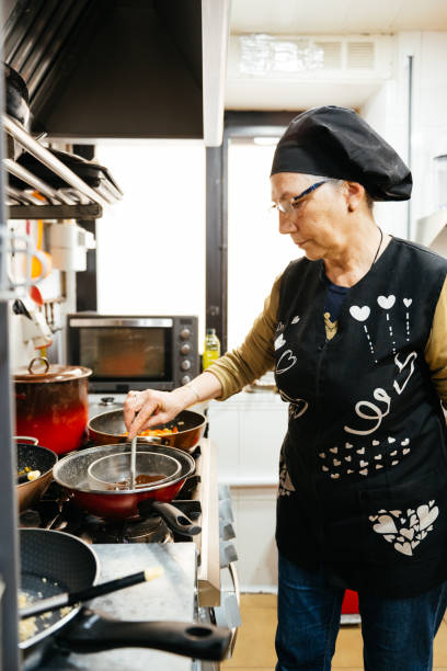 istock Woman Cooking on Stove in Professional Kitchen 2148710069