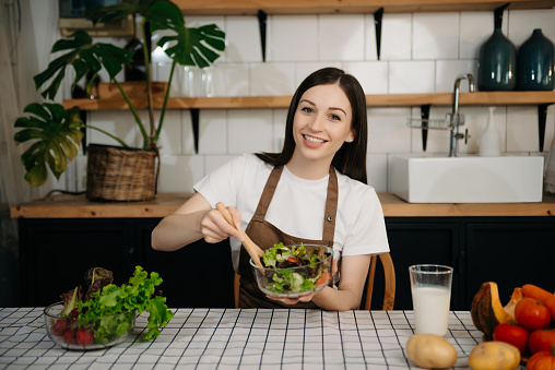 young Caucasian woman with cutting board of cut lettuce at kitchen. healthy food concept