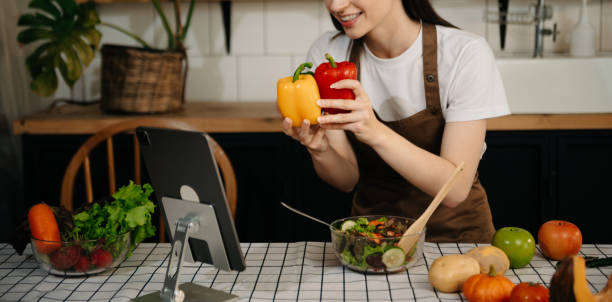 istock Young Woman cooking dinner has video call conversation in kitchen. Smiling happy female talking with friend using application on computer. 2148710198