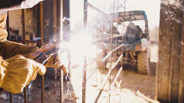 Blacksmith in a welding suit and a hamlet weld a piece of metal in the workshop. stock video
