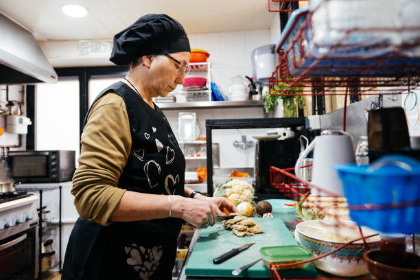 istock Experienced Chef Precisely Chopping Tofu on Cutting Board in Busy Kitchen 2148710491