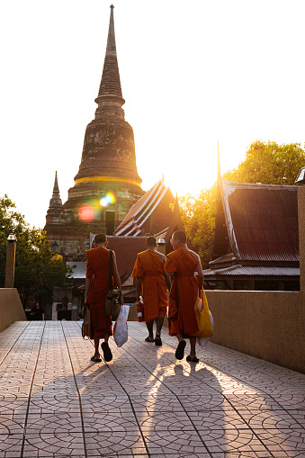 Phra Nakhon Si Ayutthaya, Thailand - April 7, 2024: Unknown monks are walking in Wat Yai Chai Mongkol, Phra Nakhon Si Ayutthaya, Thailand, at evening.
