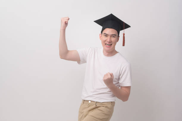 Young smiling man holding graduation hat, education and university concept