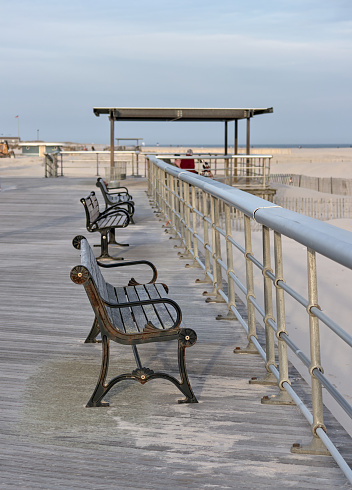 bench on the boardwalk at the beach (jones beach state park on long island nassau county new york) railing with wooden planks and sand (empty, no people) summer relaxation recreation getaway