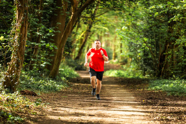 istock Mid adult man jogging on forest path 2148714439