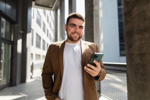 istock Business on the Move: Smiling Businessman with Smartphone by Office Building 2148715841