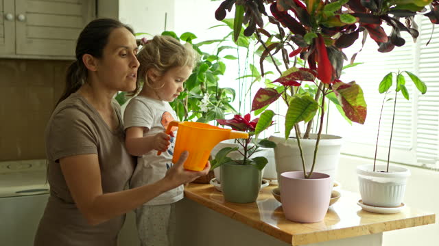 Eco Mind. Gen Alpha Girl Helps Mom Watering the Plants.
