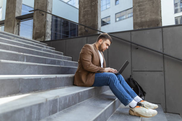 istock Contemplative Work: Handsome Man Engaged with Laptop on Office Building Stairs 2148716692