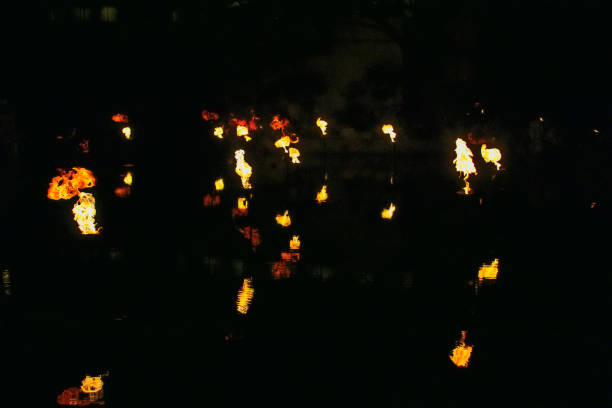 A fire show in the water, fire reflected on the water at night.