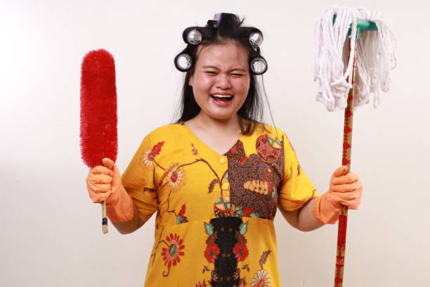 Asian housekeeper woman standing holding cleaning tools while screaming