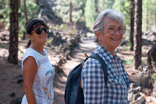 Senior couple of women enjoying healthy lifestyle hiking in the mountain forest. Elderly retired females and adventure ageless concept