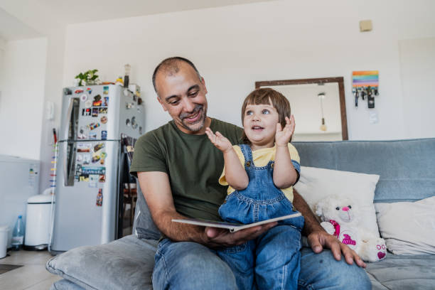 istock Father reading book to daughter on sofa at home 2148717589