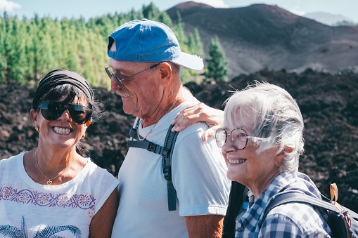 Carefree group of senior people walking in mountain volcanic in Tenerife enjoying healthy lifestyle and freedom in nature. Elderly retired and adventure ageless concept.