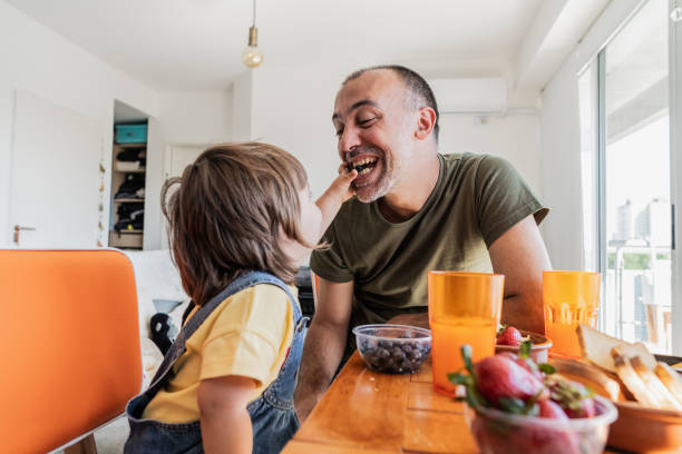 Father and daughter having fun at breakfast at apartment