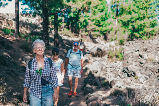 Carefree group of senior people walking in mountain footpath enjoying healthy lifestyle and freedom in nature. Elderly retired and adventure ageless concept