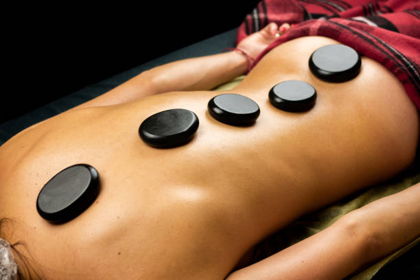 istock Black hot basalt stones are laid out on a woman's back. Massage procedure 2148719954