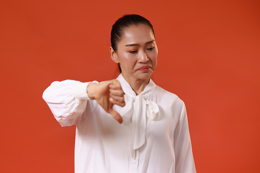 Middle age woman thump down Gesture, disagree or disappointed expression Copy space isolate red background